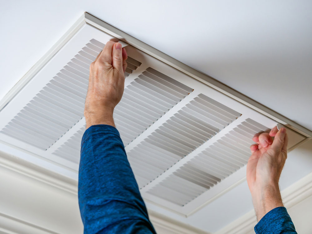 HVAC Services in Houma, LA Man opening ceiling air vent to replace dirty hvac air